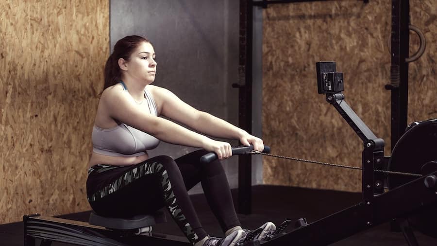 Young woman working out doing resistance pulls bon geste rameur - tirage poignee