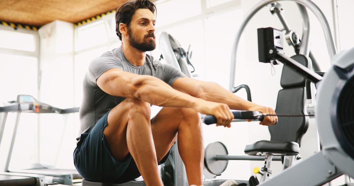Fitness young man using rowing machine bon geste rameur - tirage poignee